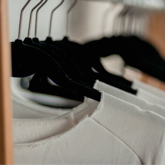 A clothing of rack with hangers holding up T shirts.